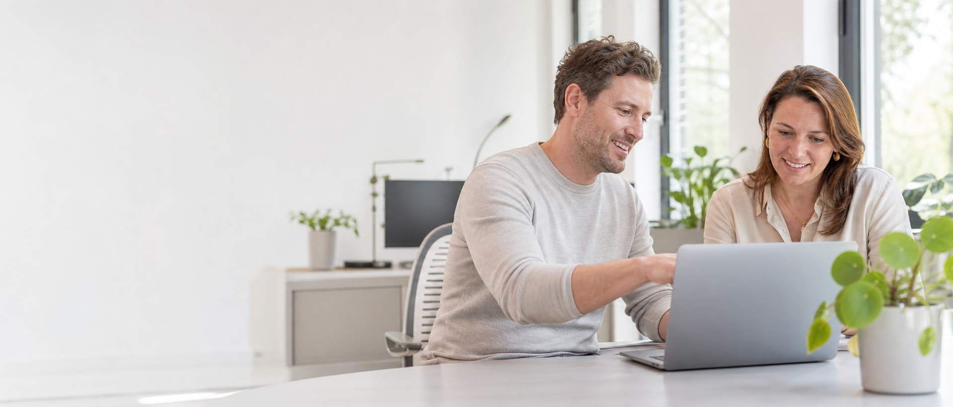 IT-specialist helpt een ondernemer met haar laptop in een lichte kantooromgeving